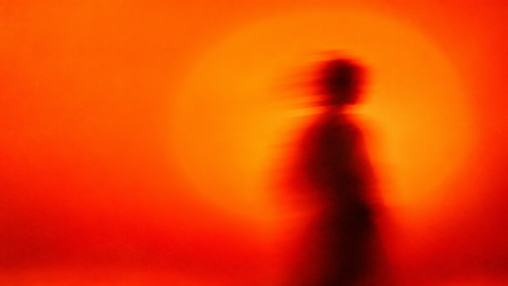 Abstract motion-blurred figure moving through orange light